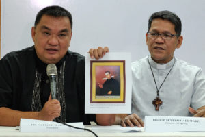 Bishop Severo Caermare of Dipolog and postulator Fr. Patrick Dalangin shows a photo of a painting of unknown date and origin, depicting Jesuit Fr. Francesco Palliola with dagger that slit his throat. The painting is presently at the archives of the Bangko Sentral ng Pilipinas in Manila. ROY LAGARDE